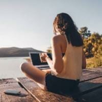 Girl on laptop by the lake