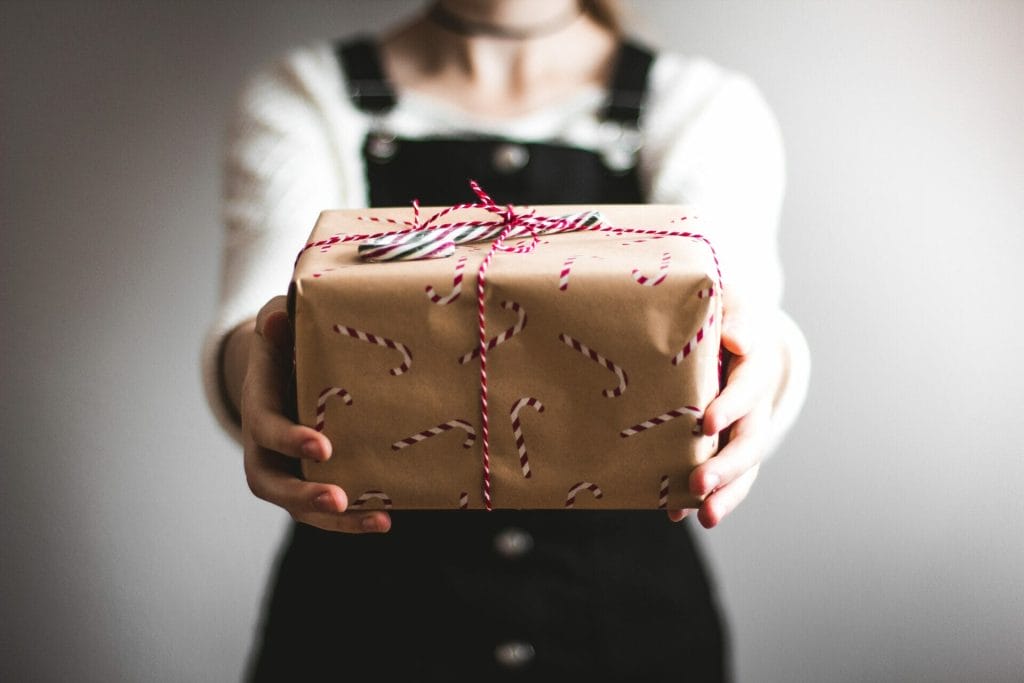 close up image of a woman holding a present with candy cane wrapping paper