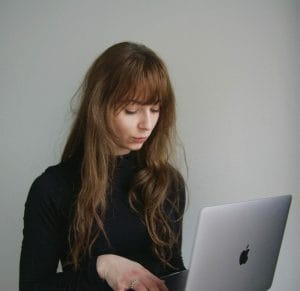 Girl working on apple laptop device reading the December 2022 newsletter