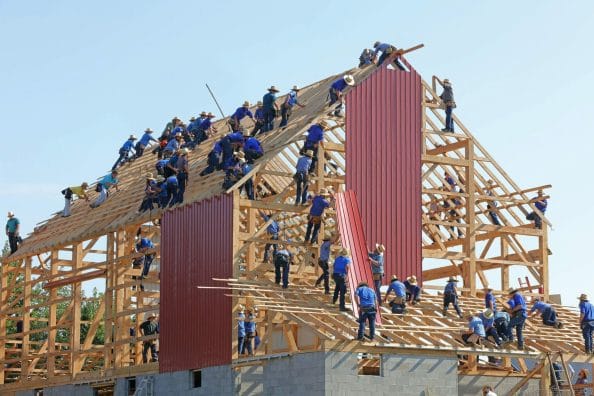 image showing a large number of construction workers in blue shirts on a roof
