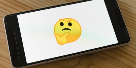 Cute yellow emoji making a thinking face on the screen of a cellphone, trying to find the right managed IT service provider.
