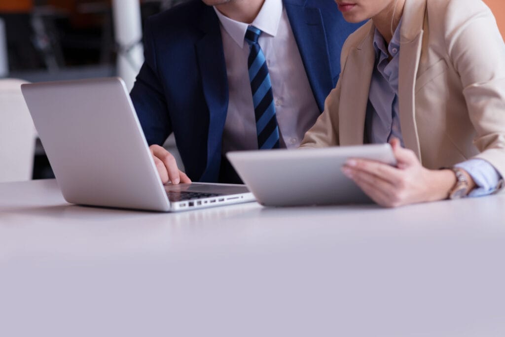 close up image of a man and woman sitting at a desk looking at a laptop