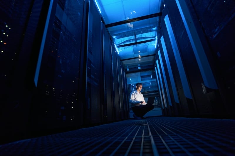 Cloud Data Security Male server administrator squatting with laptop in server room blog masthead